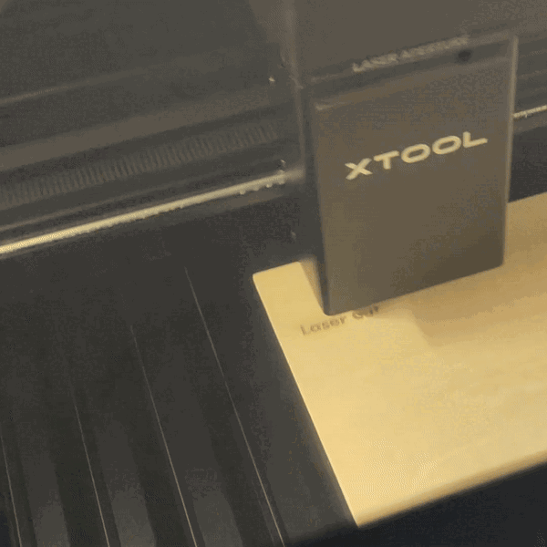 animated image showing an xTool laser cutter engraving the words laser cut onto a piece of wood, and then scoring a design